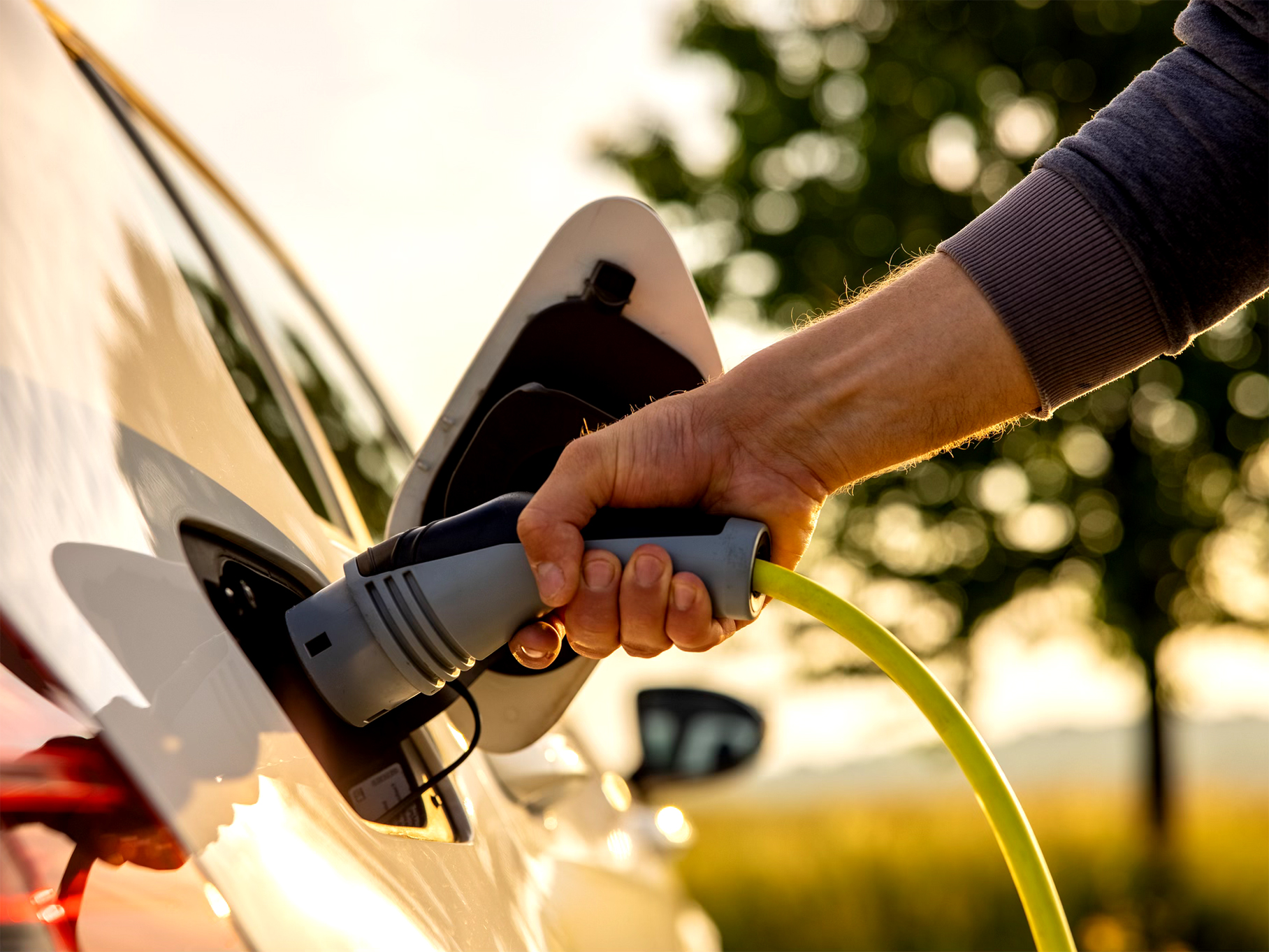 A person plugging a cable into an electric vehicle