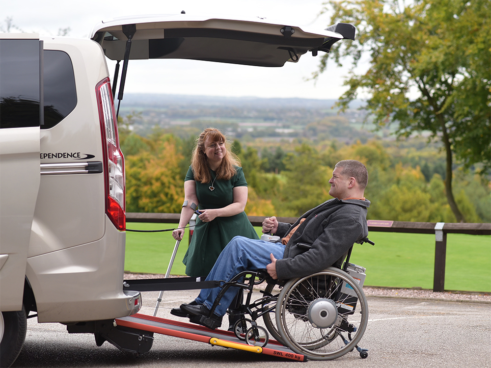 A man using a wheelchair ramp to enter a vehicle